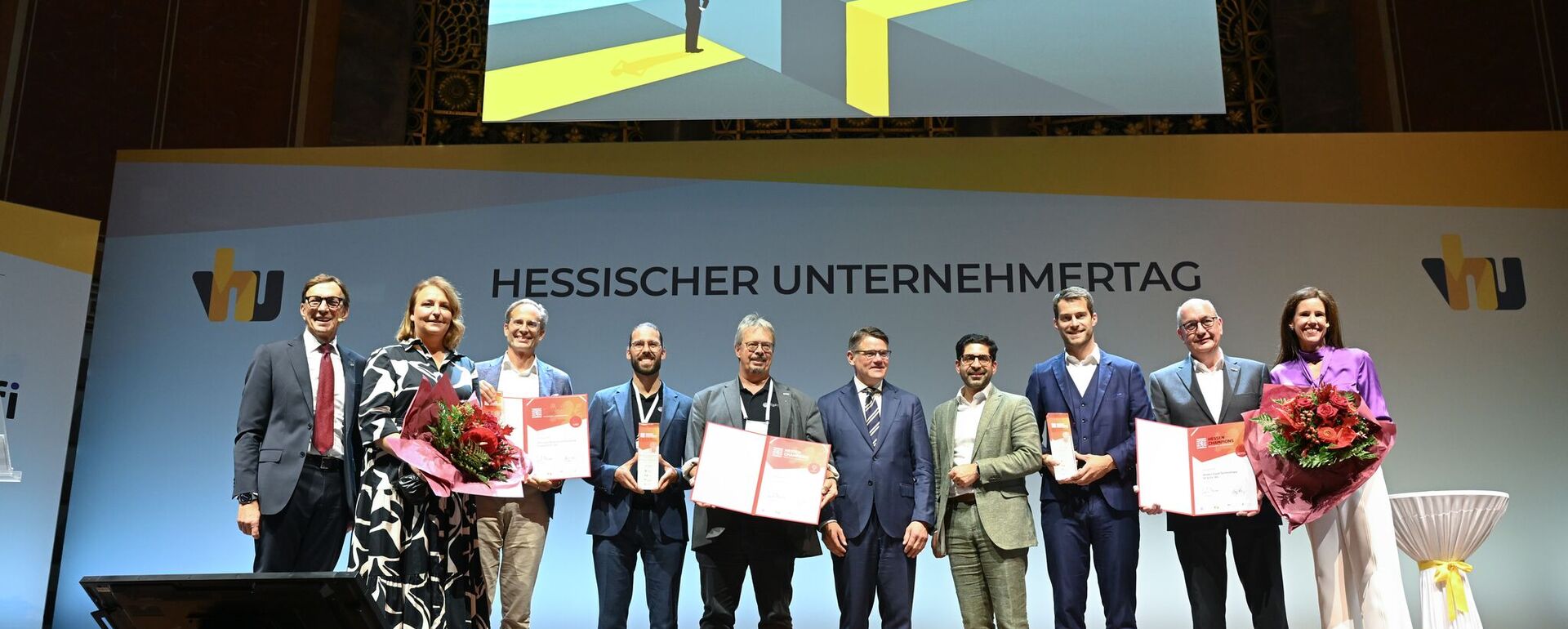 VhU-Präsident Wolf Matthias Mang, HDE-Präsident Dr. Alexander von Preen, Dr. Steffen Huth (MBG Hessen), Wirtschaftsminister Kaweh Mansoori und Moderatorin Corinna Egerer mit den "Hessen-Champions 2024" / Foto: Gerd Scheffler
